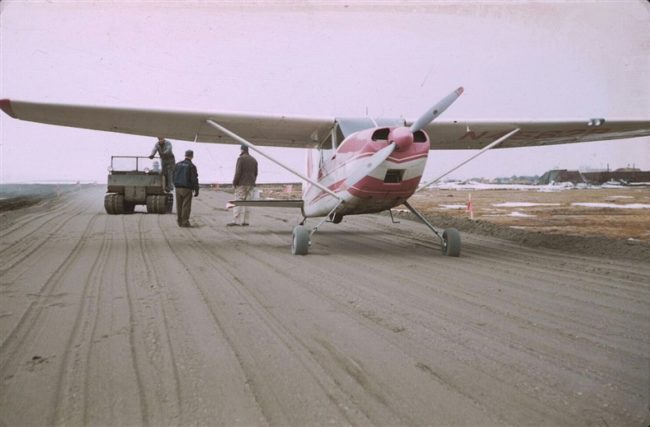 A Weasel (the tracked vehicle) is about to tow the Cessna back because it can't turn around. June 1956.