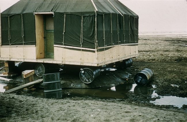 Living quarters with a oil drum foundation to keep it off the tundra. June 1956.