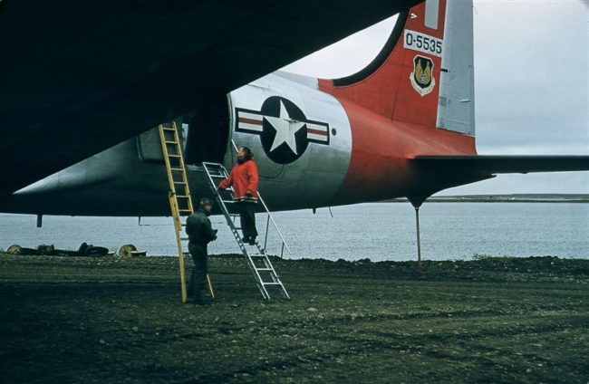 Capt Radney on the ladder peering into the C-54 interior. Sept 1956.
