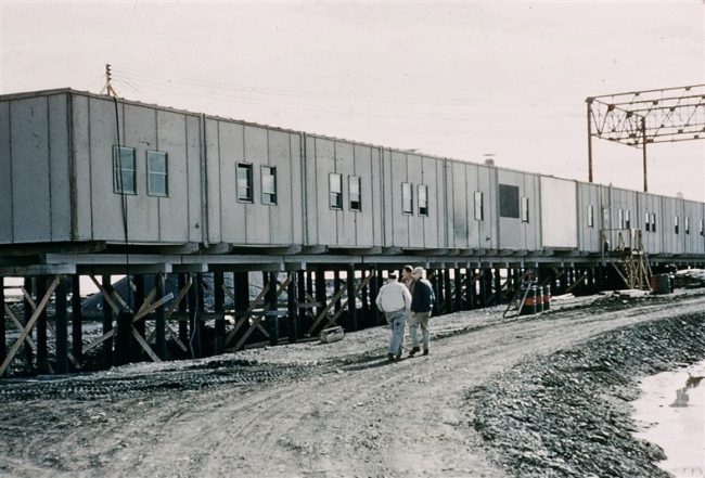 West end of the module train showing the piling that act as the foundation. The early stages of the radome platform construction can be seen on the right. June 1956.